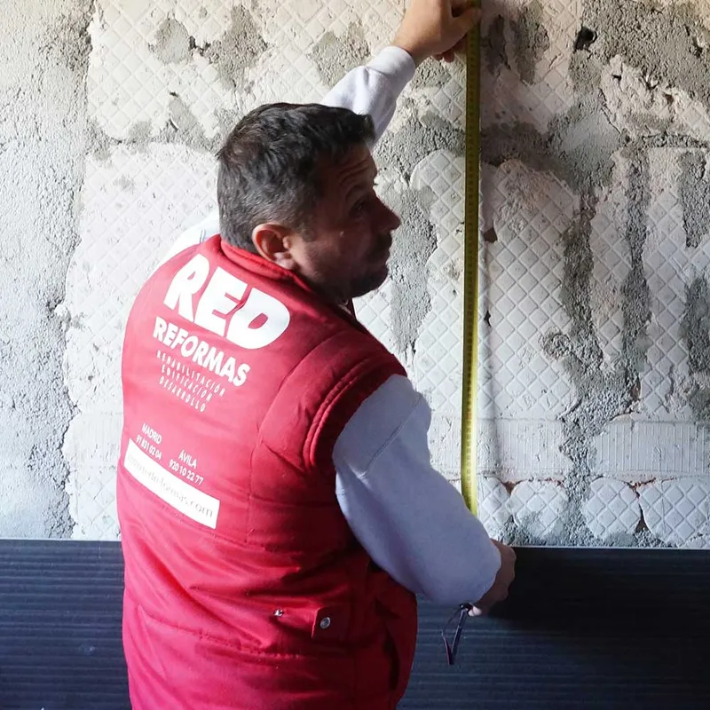 Profesional de Red Reformas midiendo una pared durante una reforma